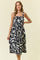 woman wearing a black and white patterned midi dress with spaghetti straps and a button-down front