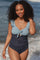woman wearing a blue and navy two-tone ruffled swimsuit with a tie front, smiling by the beach