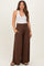woman wearing a white tank top and brown wide-leg maternity pants with pockets