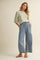 woman wearing a light green oversized sweater and wide-leg chambray pants with pockets and sandals