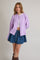woman wearing a light purple oversized cardigan and a white crop top with a denim mini skirt