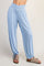 woman wearing light blue relaxed-fit pants with a wide waistband and gathered hems, paired with sandals