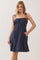 woman wearing a navy blue sleeveless smock dress with adjustable straps and pockets