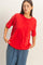 woman wearing a vibrant red oversized t-shirt with a front pocket paired with loose blue pants