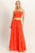 woman wearing an orange smocked crop top and a matching tiered maxi skirt
