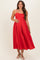 woman wearing a red maternity dress with adjustable straps, showing a visible baby bump and a flowy skirt