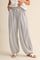 woman wearing black and white striped loose-fitting harem pants with a drawstring waist and sandals