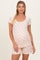 woman wearing a light peach floral short sleeve maternity pajama set with a visible baby bump