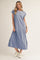 woman wearing a light blue short sleeve maxi dress with side slits and white trim, styled with white sneakers