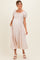 woman wearing a light pink maternity dress with puff sleeves and a tie front, showcasing her baby bump