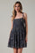 woman wearing a navy blue floral print sundress with tie shoulder straps and tiered ruffles