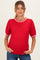woman wearing a red maternity sweater with a textured fabric and striped neckline, showing her baby bump