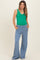 woman wearing a green maternity tank top and blue wide-leg maternity pants with pockets