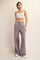 woman wearing a white cropped tank top and gray high-waisted flared pants with an elastic waistband