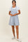 woman wearing a light blue floral print overall dress over a white t-shirt and white sneakers