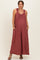 woman wearing a rust ruffled strap maternity jumpsuit with pockets and a visible baby bump