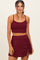 woman wearing a burgundy ribbed crop top and matching mini skirt with drawstring detail