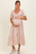 woman wearing a pink floral maternity dress and holding her baby bump