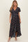 woman wearing a black floral wrap maternity dress with short sleeves and a tiered hem, showcasing her baby bump