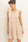 woman wearing a sleeveless beige tiered dress with a loose fit and round neckline