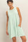 woman wearing a light mint green sleeveless tiered dress with pockets