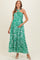 woman wearing a green floral patterned maternity maxi dress with a knotted halter neck and pockets, showing her baby bump