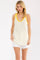 woman wearing a white tank top with yellow polka dots and a yellow trim, paired with white shorts