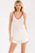 woman wearing a cream spaghetti strap tank top with red floral print and matching trim, paired with white distressed shorts