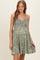 woman wearing a green floral maternity sundress with a smocked bodice and a relaxed skirt, showcasing her baby bump