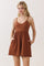 woman wearing a rust-colored ribbed romper with adjustable straps and pockets