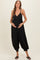 woman wearing a black maternity jumpsuit with a button-up front and balloon-style legs, holding her baby bump