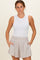 woman wearing a white sleeveless maternity top and beige shorts, smiling at the camera