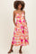 woman wearing a floral print maternity dress with spaghetti straps and pockets, showcasing her baby bump