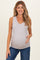 woman wearing a light gray v-neck maternity tank top and holding her baby bump while smiling