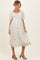 woman wearing a white floral print maternity dress with short puff sleeves and a square neckline, showcasing a baby bump
