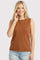 woman wearing a rust-colored sleeveless top and smiling with hand touching her face