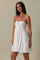 woman wearing a white strapless sundress with a ruffled hem and a front button detail