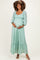 woman wearing a mint green lace maternity dress with puff sleeves and a tiered hem, showing off her baby bump