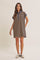 woman wearing a striped brown and navy polo dress with short sleeves and a collar, styled casually with sneakers