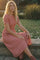 woman wearing a red and white gingham print midi dress sitting by a pond with tall grass in the background