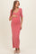 woman wearing a pink ribbed maternity maxi dress, holding her baby bump with a side slit design