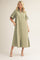 woman wearing a long green button-up shirt dress with short sleeves and side pockets