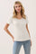 woman wearing a white short sleeve ribbed top with button detail and ruffled hemline