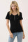 woman wearing a black short sleeve top with buttons and ruffle details, paired with light blue jeans