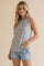 woman wearing a floral sleeveless top in pastel colors and light blue denim shorts