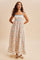 woman wearing a floral maxi dress with thin blue straps and a fitted bodice, standing with hands on hips
