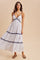 woman wearing a white maxi dress with navy stripes and a tie-front detail, paired with flip-flops