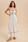woman wearing a white maxi dress with black trim and spaghetti straps