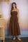 woman wearing a brown spaghetti strap midi dress with smocked bodice and relaxed fit standing by a colorful backdrop