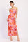 woman wearing a pink and orange floral maxi dress with a side slit and halter neckline